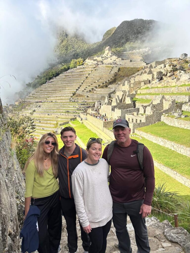 Family at Machu Picchu with panoramic views of the Inca citadel, terraces, and cloud forest mountains